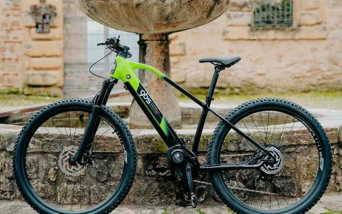 Electric bike parked near a stone fountain in Olbia.