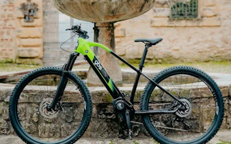 Electric bike parked near a stone fountain in Olbia.