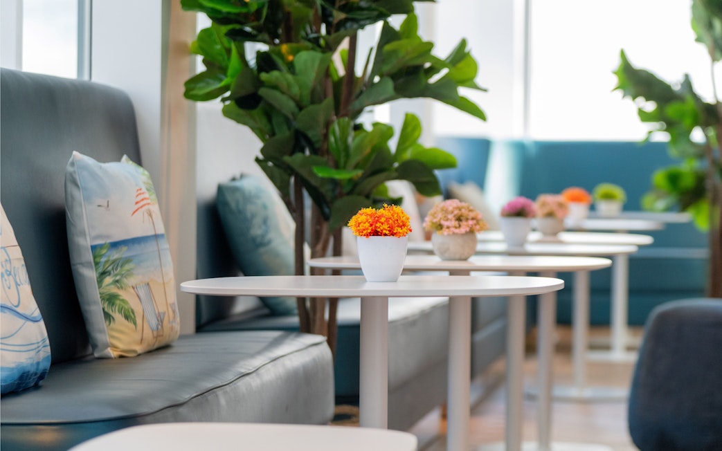 Seating area with plants and tables at Plaza Premium Lounge, London Gatwick Airport.