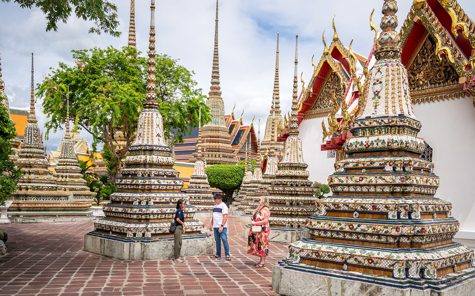 Wat Pho stupas in Bangkok with tourists exploring the temple grounds.