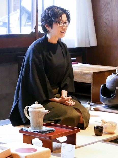 Guide demonstrating matcha making process in traditional Japanese tea room.
