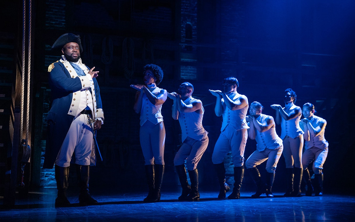 Stage performance of Hamilton with actors in period costumes.