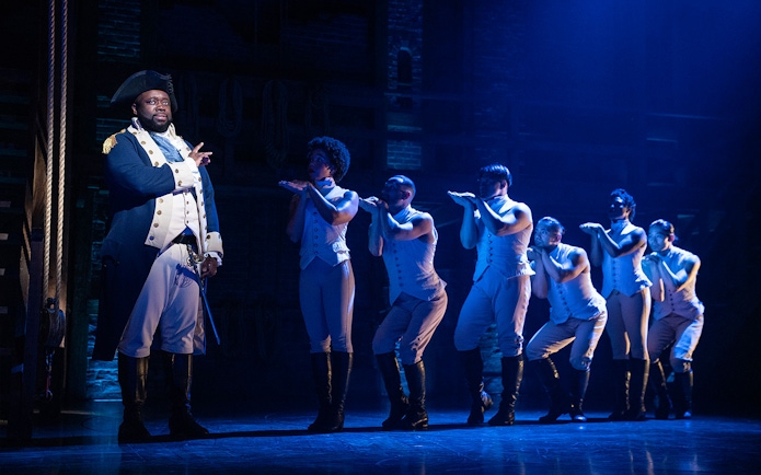 Stage performance of Hamilton with actors in period costumes.