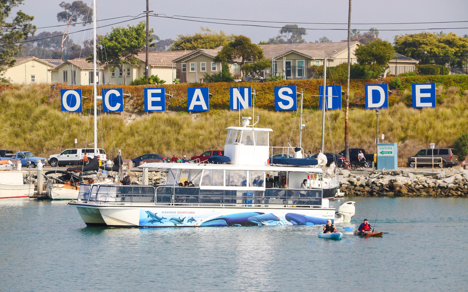 Whale watching boat in Oceanside Harbor, San Diego, with kayakers nearby.