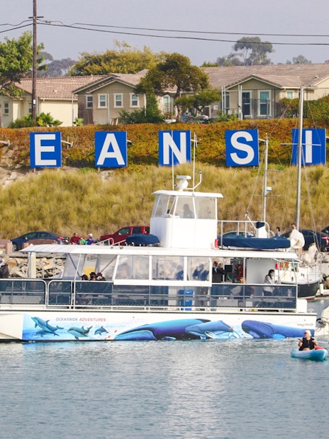 Whale watching boat in Oceanside Harbor, San Diego, with kayakers nearby.