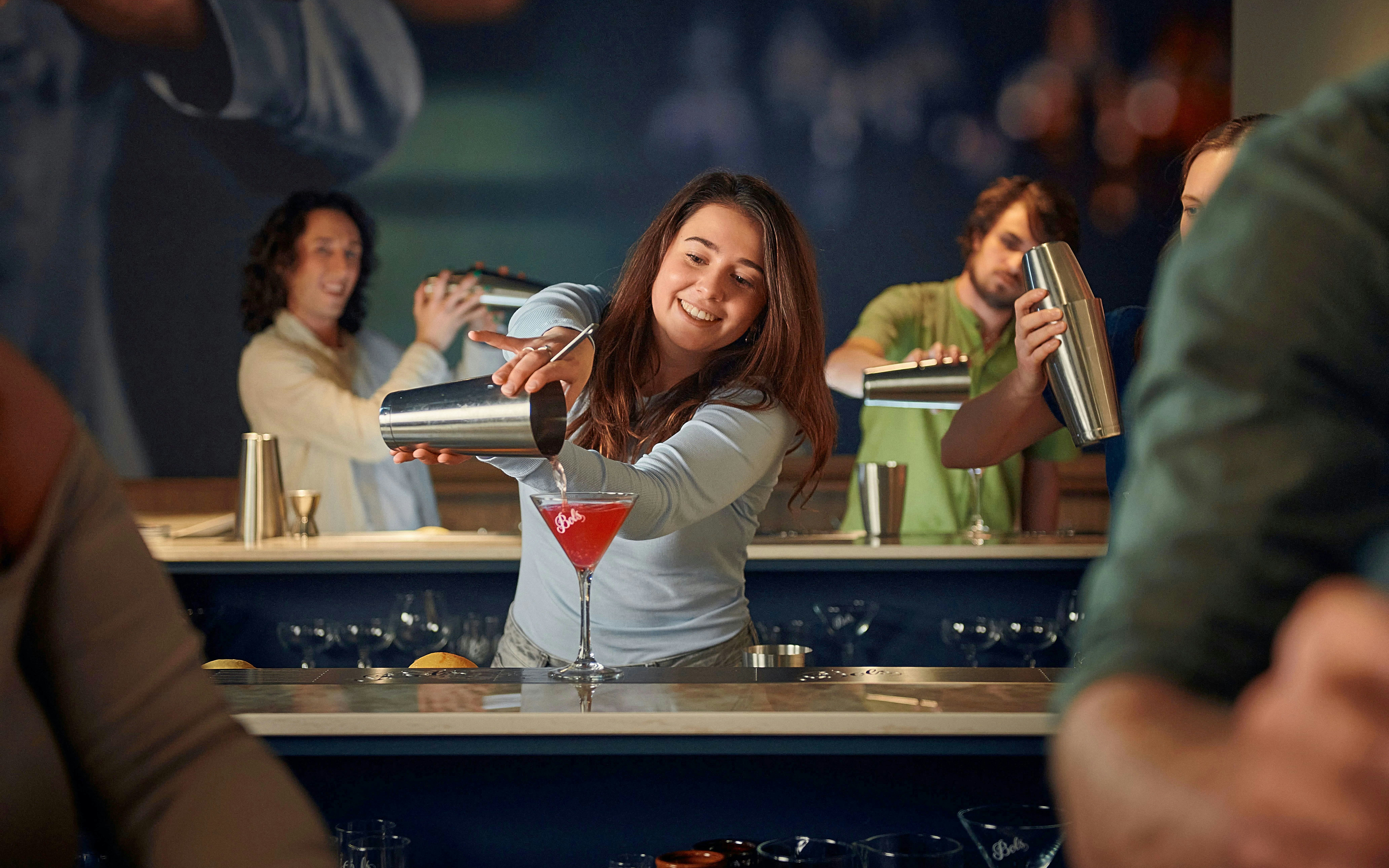 Participants enjoying a cocktail making workshop, mixing drinks at a bar.