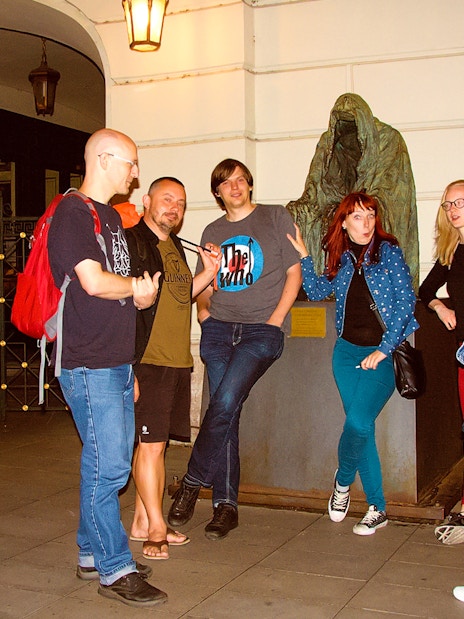 Group of tourists on a Ghosts and Legends of Prague tour near a cloaked statue.