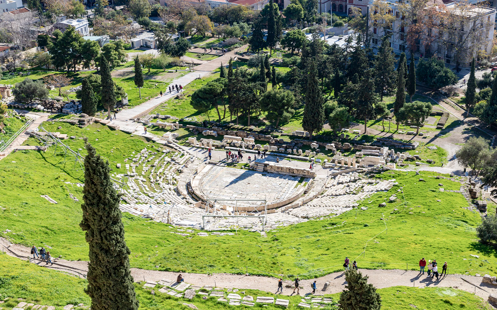 Theater of Dionysus ruins surrounded by greenery in Athens, Greece.
