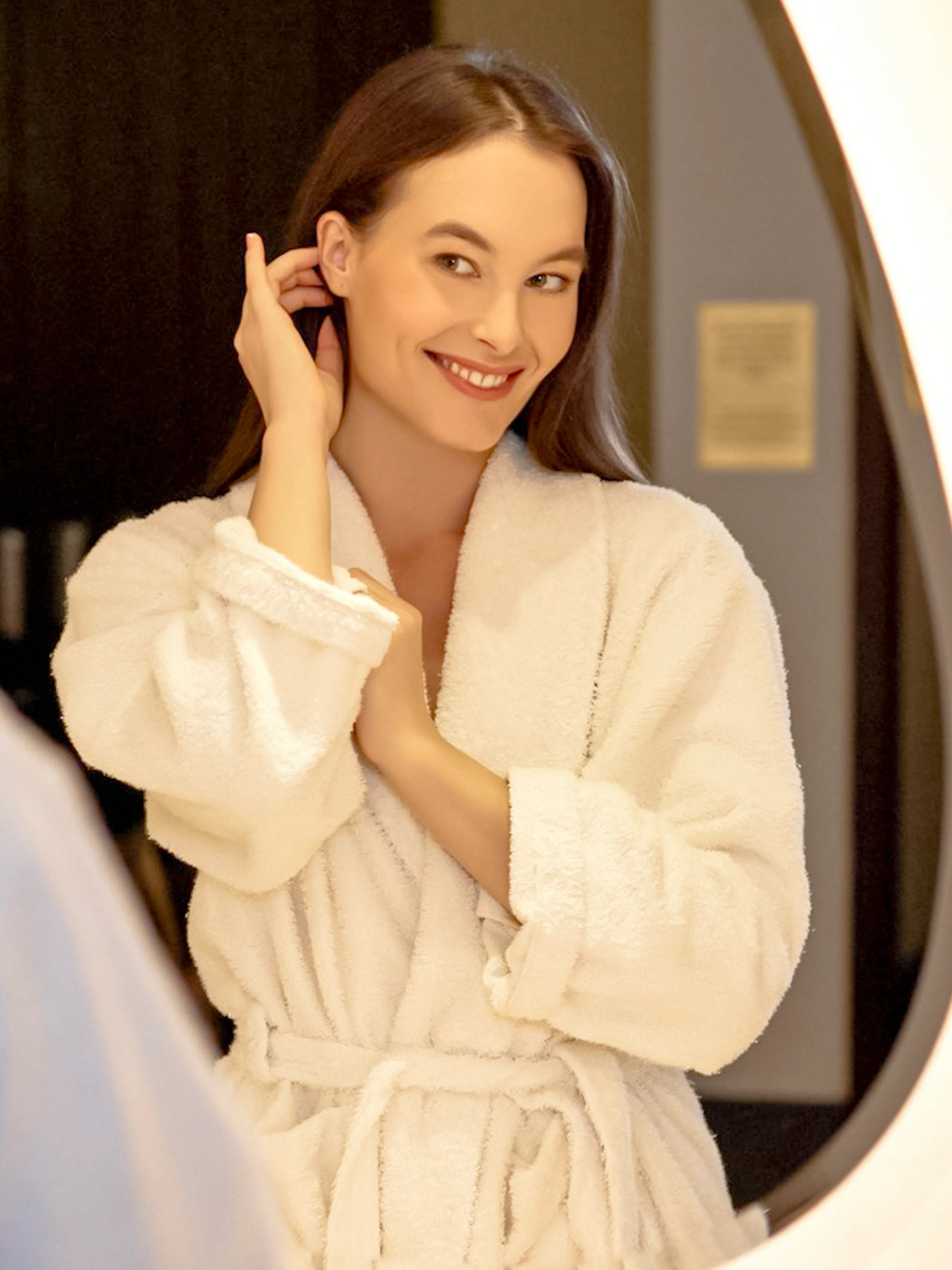 Person in a robe smiling in front of a mirror at Mandala Day Spa.
