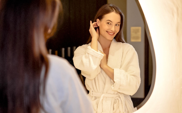 Person in a robe smiling in front of a mirror at Mandala Day Spa.