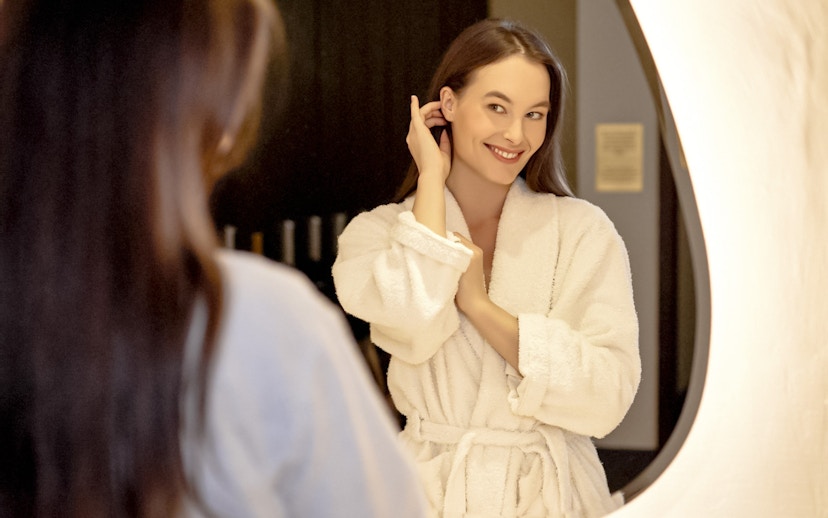 Person in a robe smiling in front of a mirror at Mandala Day Spa.