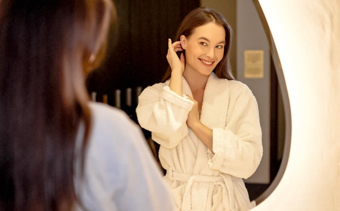 Person in a robe smiling in front of a mirror at Mandala Day Spa.
