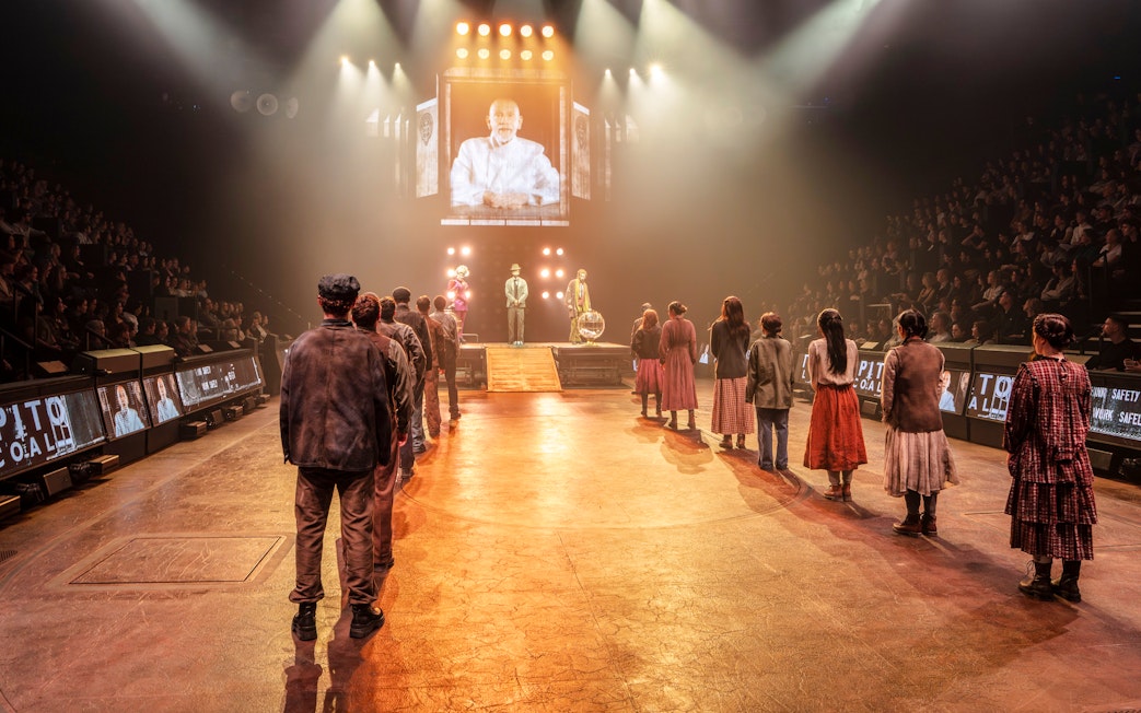Hunger Games West End show stage performance with actors in line facing a large screen.