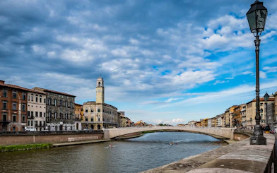 Pisa cityscape with Arno River and historic buildings, viewed during a guided tour from Florence.