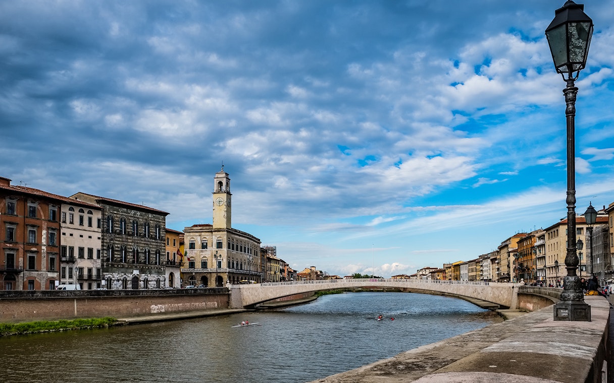Pisa cityscape with Arno River and historic buildings, viewed during a guided tour from Florence.