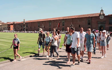 Tour group walking in Pisa with a guide holding a flag, part of a guided tour from Florence.