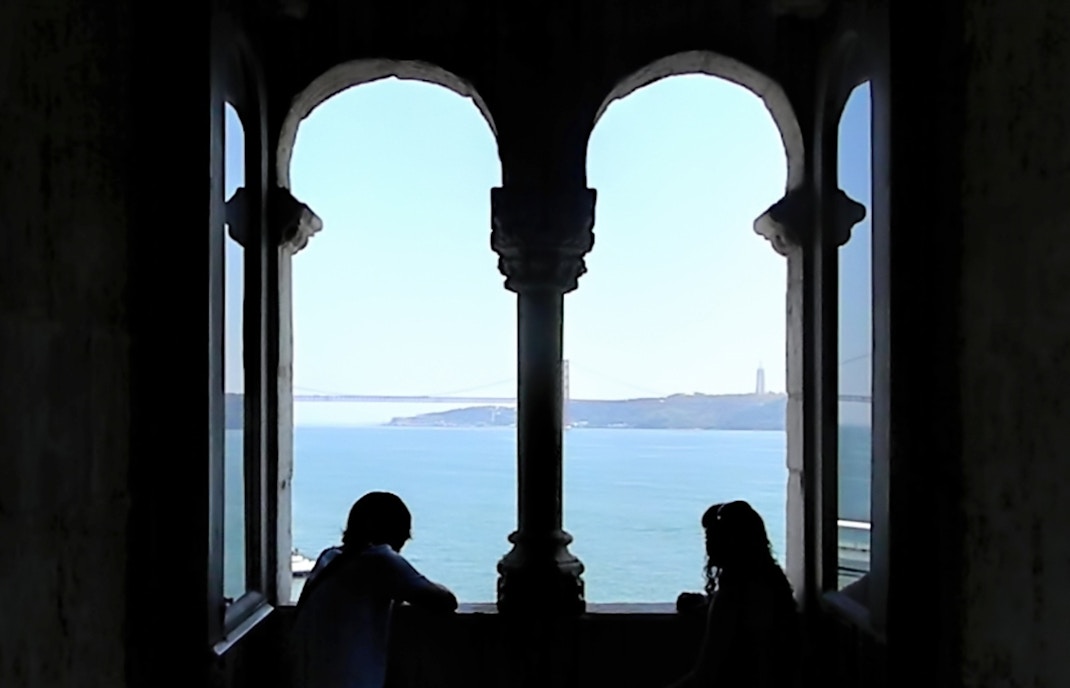 Belem Tower in Lisbon, Portugal, with tourists exploring the historic waterfront landmark.