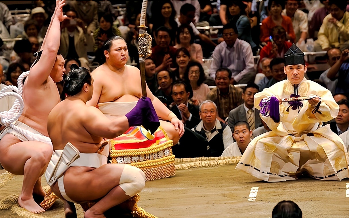 Sumo wrestlers performing pre-match ritual in a Japanese sumo ring.