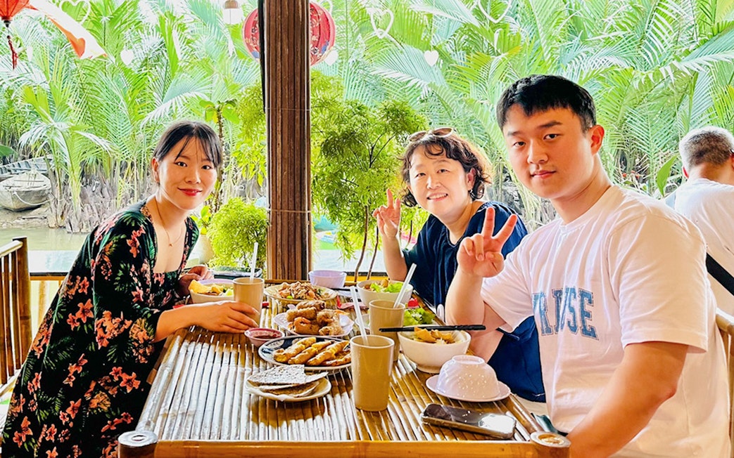 Group enjoying lunch at a riverside restaurant in Hoi An, Vietnam.