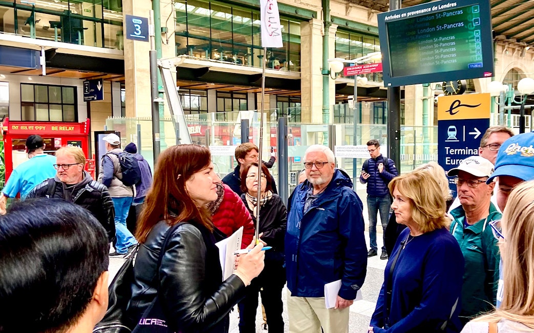 Group of tourists at a Paris train station, preparing for a day trip with lunch on the Eiffel Tower.