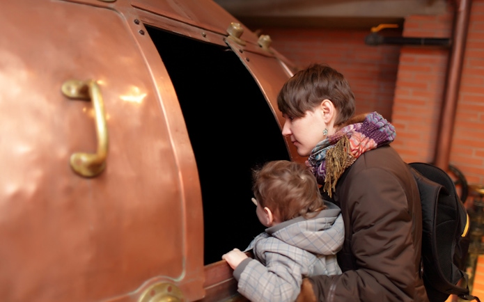 Visitors exploring a copper brewing vat at a Prague museum.