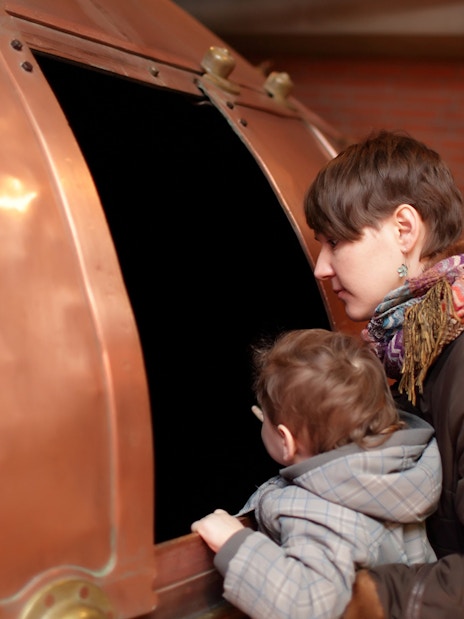 Visitors exploring a copper brewing vat at a Prague museum.