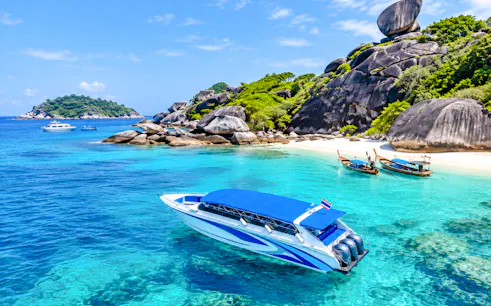 Speedboat near Similan Island's rocky shore and clear waters, Phuket day trip.