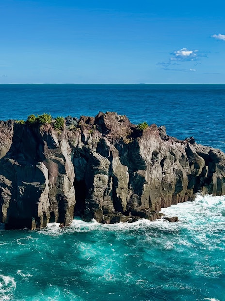 Rugged volcanic cliffs at Jogasaki Coast, Izu Peninsula, Japan, with ocean waves below.