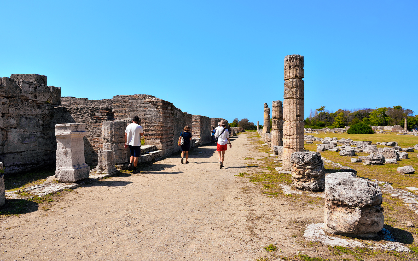 Visitors walking through ancient ruins at Paestum Archaeological Park, Italy.