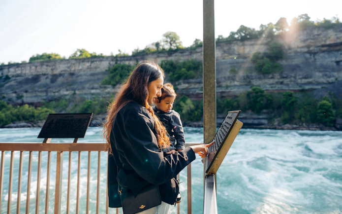 Visitors reading an information board at White Water Walk, Niagara Parks.