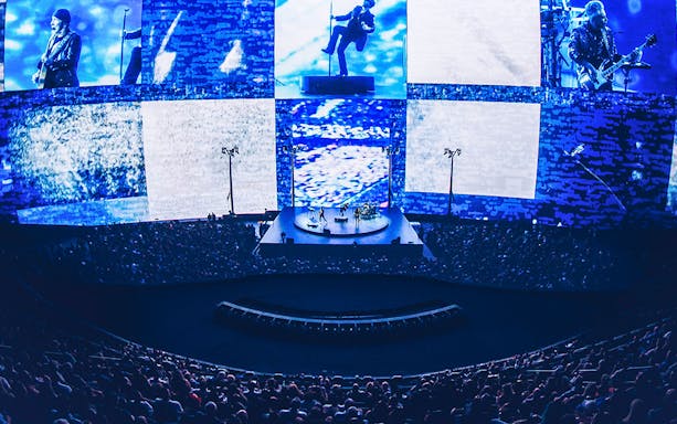 Concert at Sphere Las Vegas with band performing on stage, immersive visuals surrounding audience.