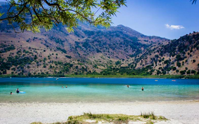 Lake Kournas with swimmers and mountains in Crete, part of Chania full-day tour.