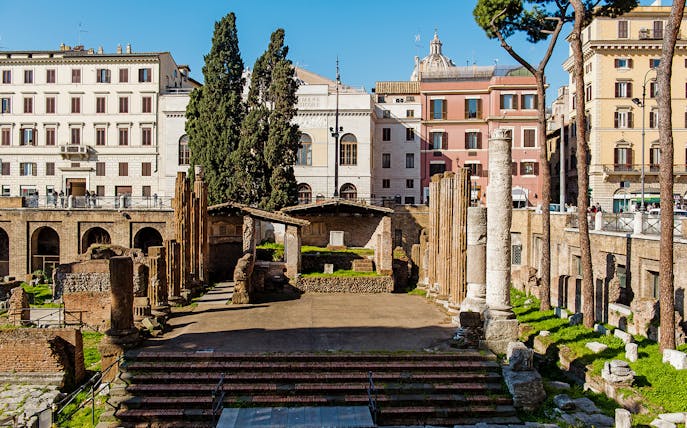 Largo di Torre Argentina ruins in Rome with ancient columns and surrounding buildings.