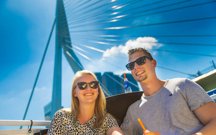 Guests enjoying a river cruise in Rotterdam with the Erasmus Bridge in the background.