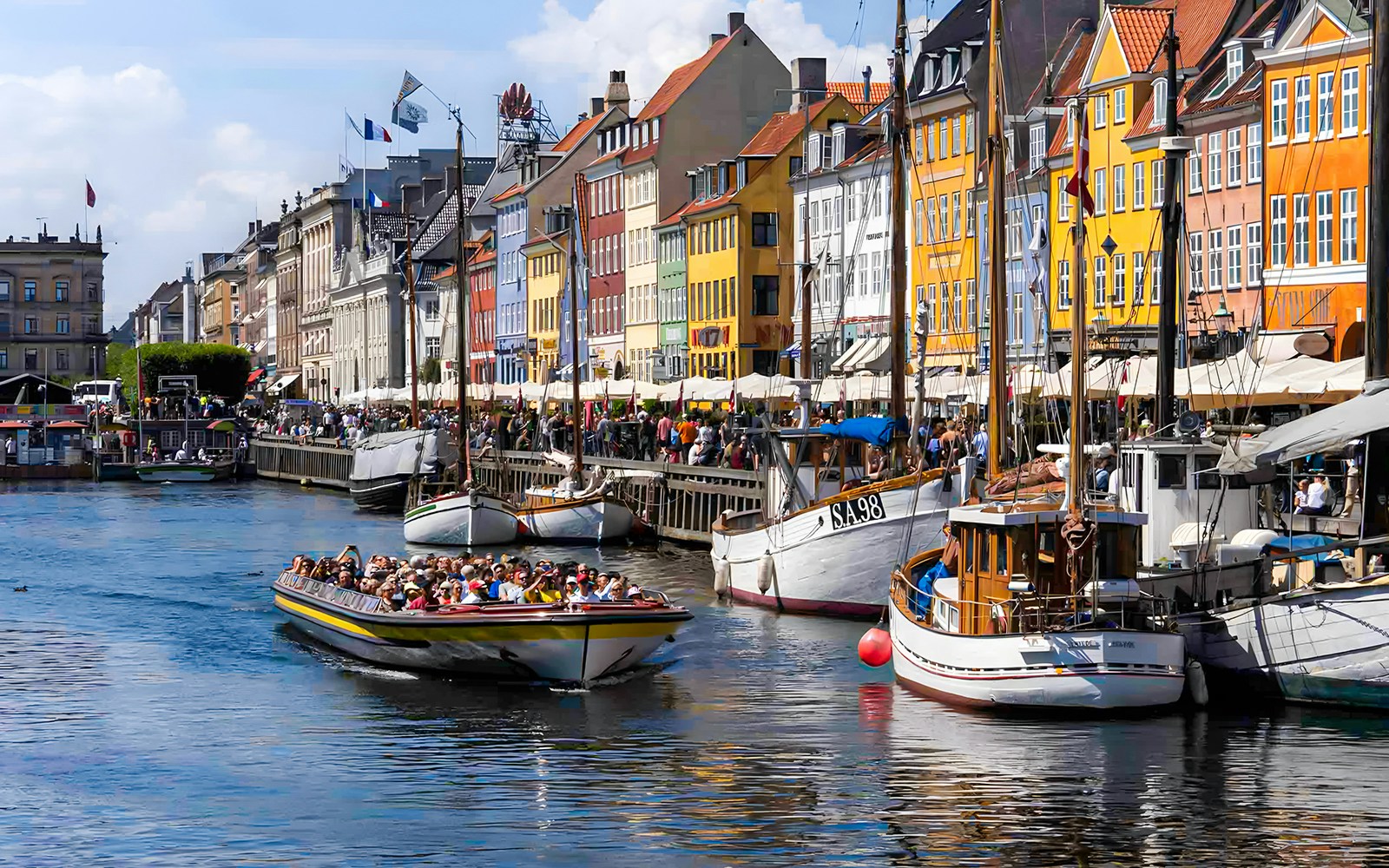 Tour boat navigating Copenhagen canals with historic buildings in view