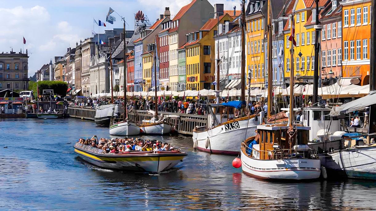 Tour boat navigating Copenhagen canals with historic buildings in view
