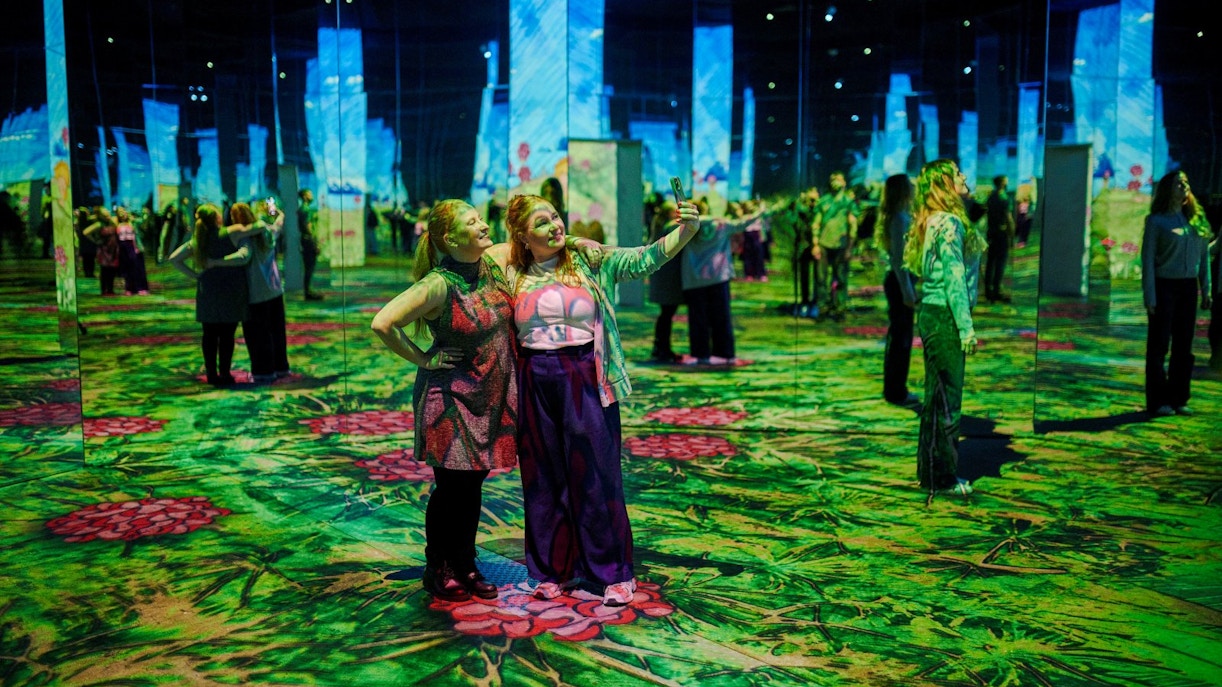 Guests taking selfies at Phoenix des Lumières art center with immersive digital displays.
