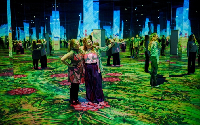 Guests taking selfies at Phoenix des Lumières art center with immersive digital displays.
