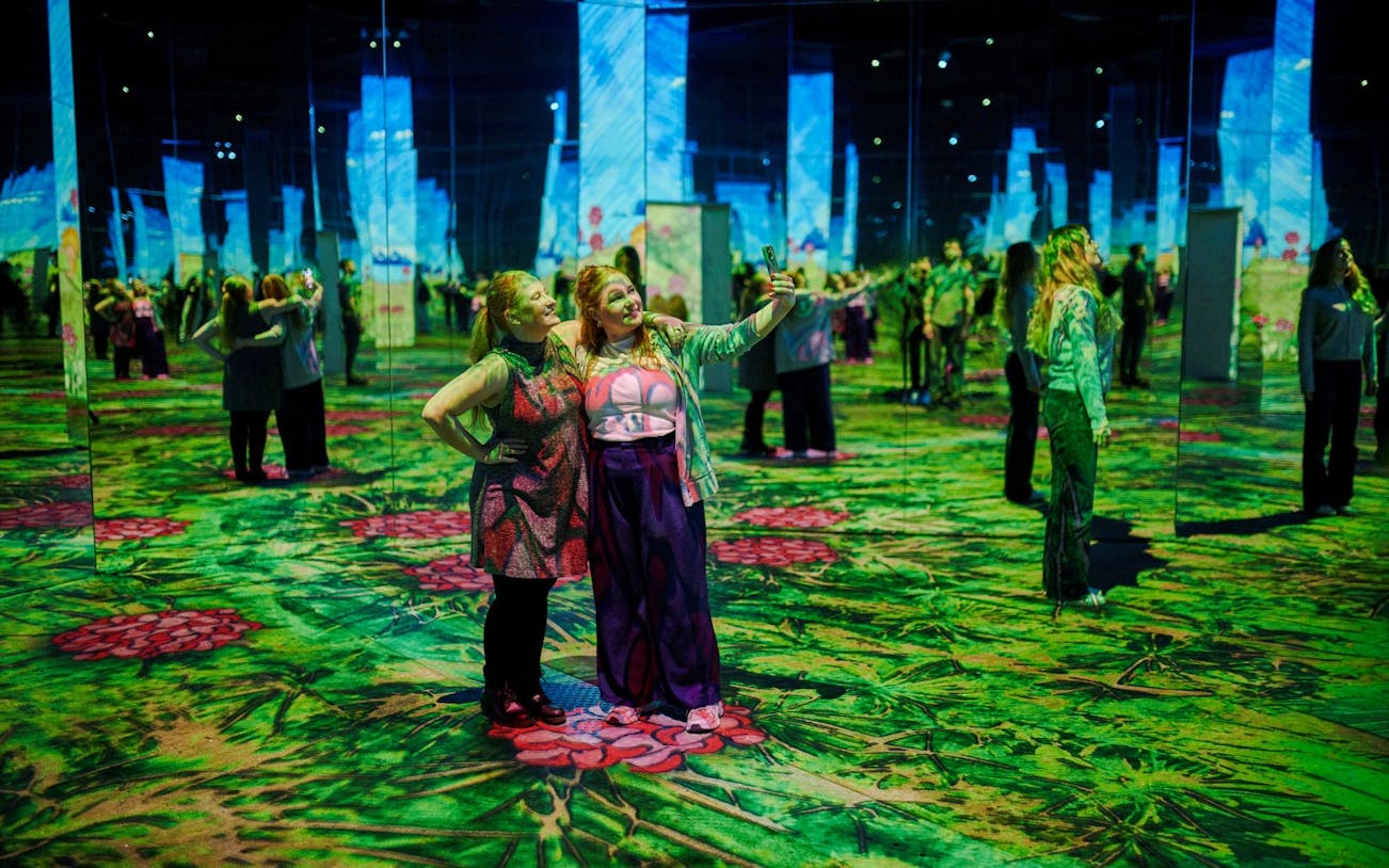 Guests taking selfies at Phoenix des Lumières art center with immersive digital displays.