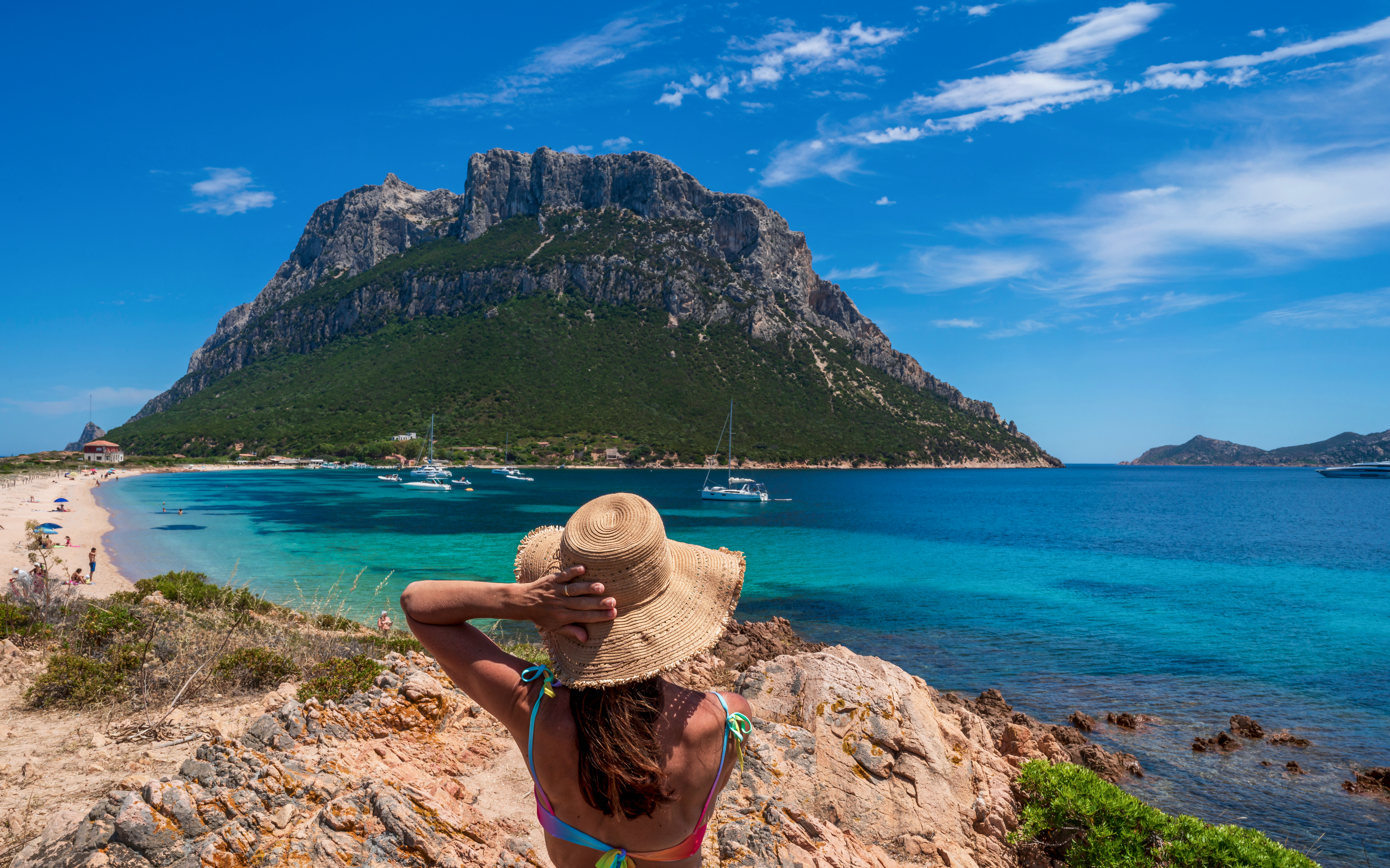 Girl in sun hat overlooking Tavolara Island beach and sea, Sardinia.