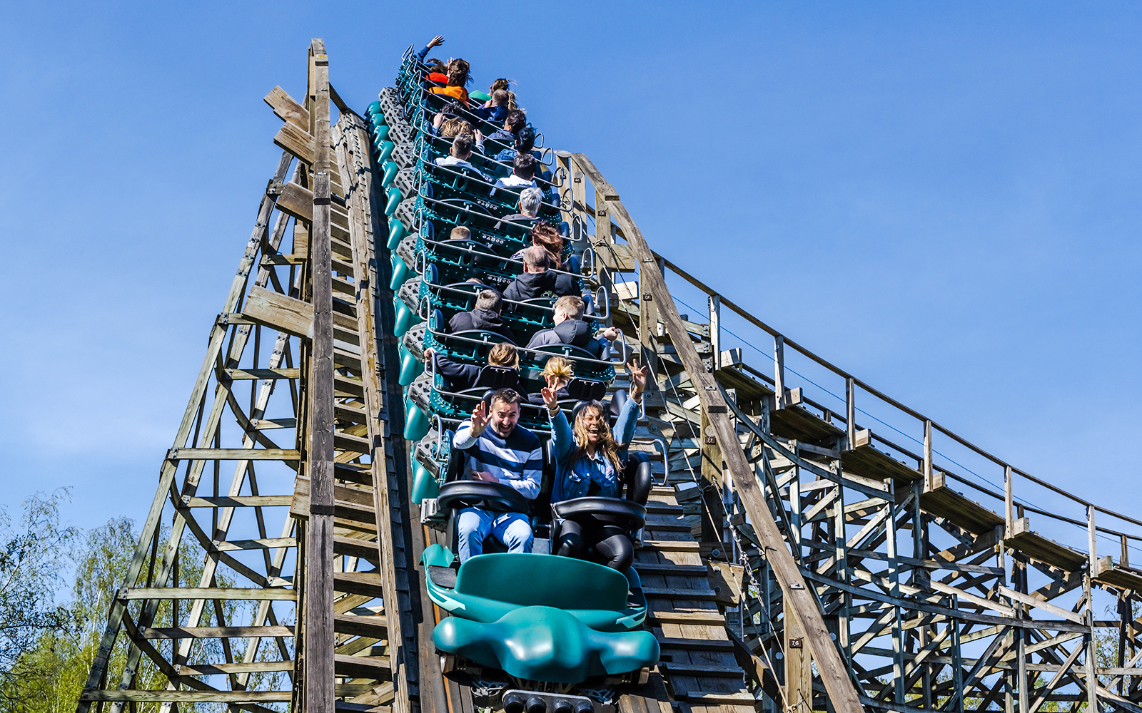 Roller coaster at Parc Asterix with riders descending a wooden track.