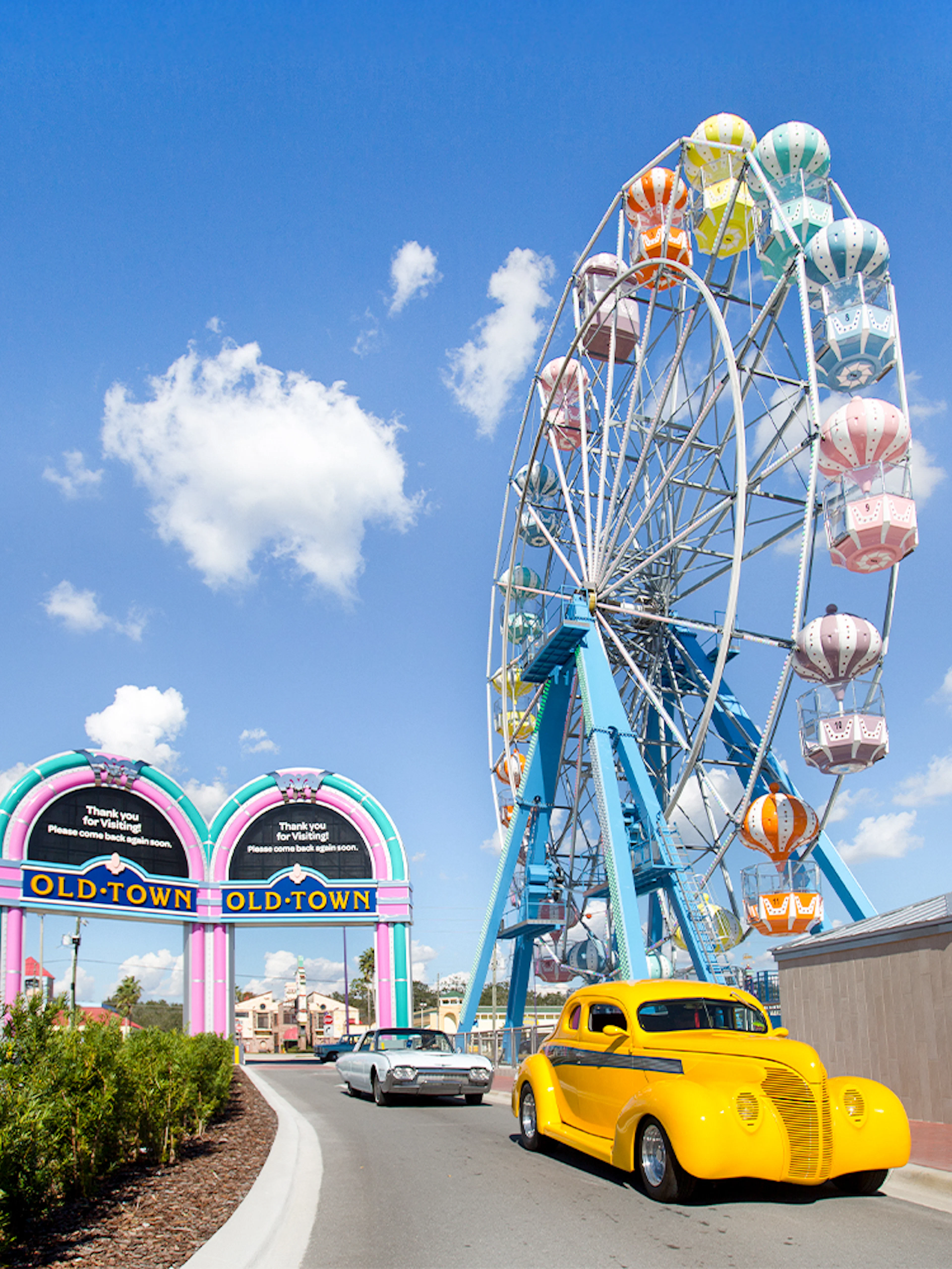 Old Town Ferris Wheel in Orlando with vintage cars on the road.