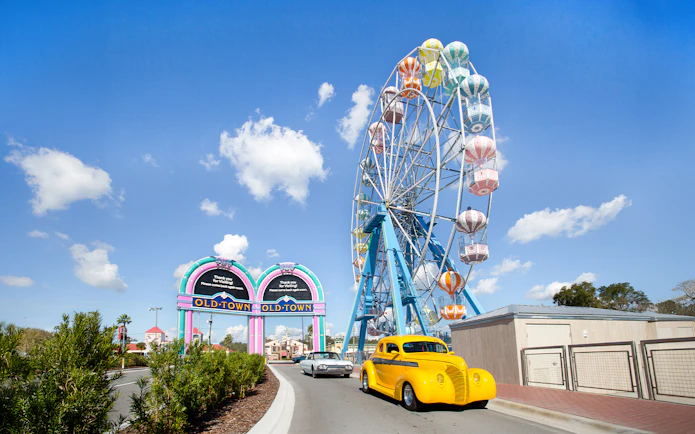Old Town Ferris Wheel in Orlando with vintage cars on the road.