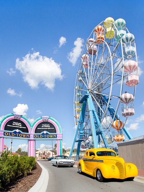 Old Town Ferris Wheel in Orlando with vintage cars on the road.