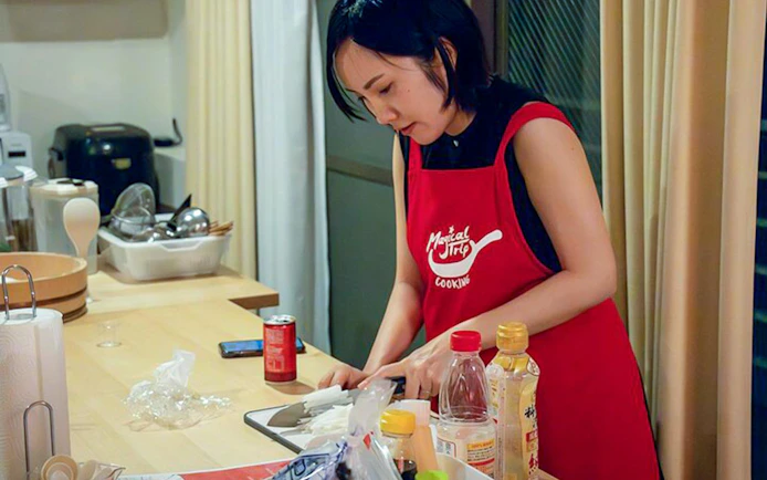 Person preparing ingredients in a Tokyo izakaya-style cooking class kitchen.