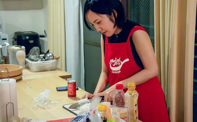 Person preparing ingredients in a Tokyo izakaya-style cooking class kitchen.