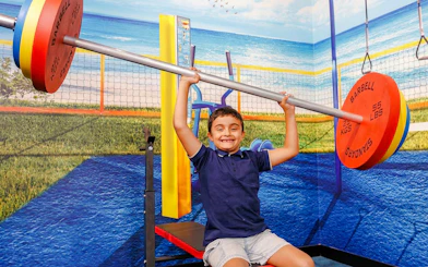 Child lifting oversized barbell in TRICKD: Illusions, Fun, & More exhibit.