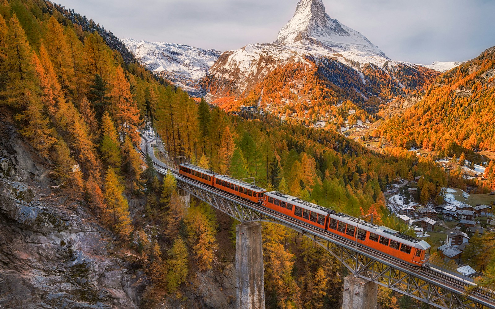 autumn on snowy Matterhorn peak with blue cloudy sky , bridge and Gornergrat tourist train in Zermatt Switzerland