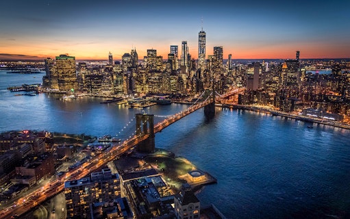 Brooklyn Bridge and Manhattan skyline at dusk during NYC helicopter night tour.