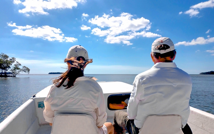 Guests on airboat tour in national park, viewing open water and distant trees.